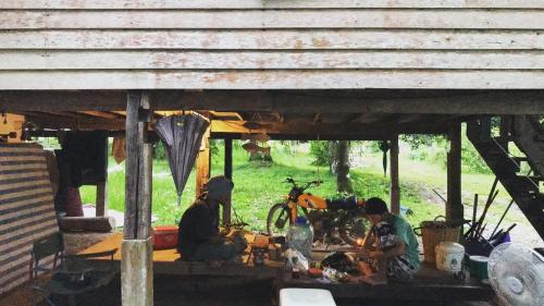 a group of three people sitting under a building at Kom buds garden in Ko Yao Noi