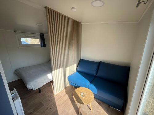 Cette petite chambre dispose d'un canapé bleu et d'un lit. dans l'établissement Studios au camping, à Saint-Martin-Plage