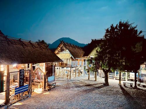 a group of buildings with a tree in front of them at Ban Anoulak - Cultural Preservation Village in Nam Bak