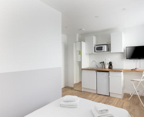 une cuisine avec des armoires blanches et un micro-ondes dans l'établissement Paimpont, à Brest