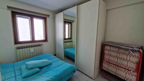a bedroom with a blue bed and a mirror at Bilocale in residence San Nicola 3 in San Massimo