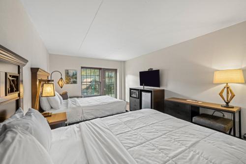 a bedroom with two beds and a desk and a television at Black Bear Inn & Suites in Gatlinburg