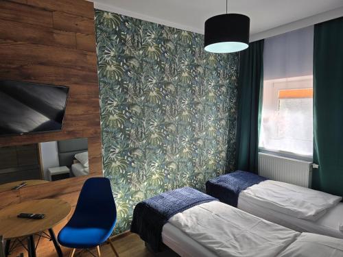 a room with two beds and a table and a wall at Eldom-NOCLEGI, Kolejowa 15 Wągrowiec in Wągrowiec