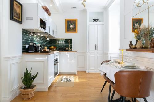 une cuisine avec des armoires blanches et une table et des chaises dans l'établissement Studio charmant Parking & terrasse près du centre, à Nantes