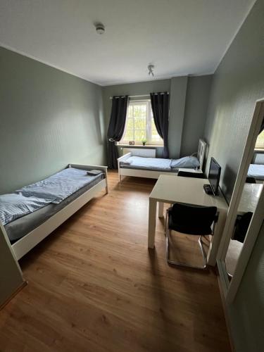 a room with two beds and a desk and a table at Bett4-you Pinneberg - Prisdorf in Prisdorf