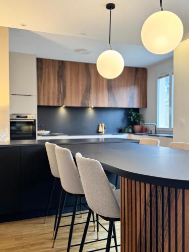 - une cuisine avec un bar avec des chaises et des lumières dans l'établissement La Maison d Ernest, avec jardin, à deux pas de la gare, à Rennes