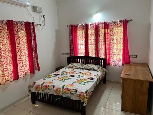 a small bed in a room with red curtains at Safari Homestay, Malayattoor in Kodanad
