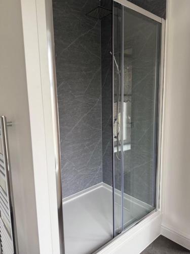 a shower with a glass door in a bathroom at Town Centre Cosy Flat in Merthyr Tydfil