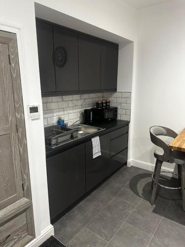 a kitchen with black cabinets and a sink and a table at Town Centre Cosy Flat in Merthyr Tydfil