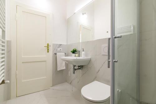 a white bathroom with a toilet and a sink at Casa Calise Elegant 1920s Villa with Garage in Siena