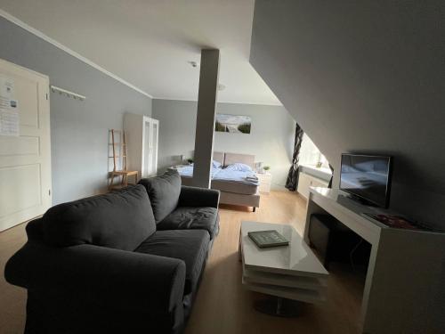 a living room with a couch and a tv at Bett4-you Pinneberg - Prisdorf in Prisdorf