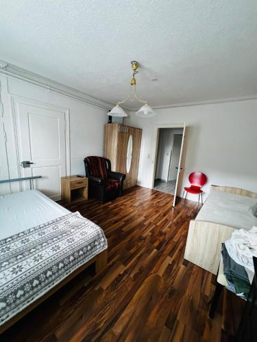 a bedroom with two beds and a chair and wooden floors at Oberbaselweg in Weil am Rhein