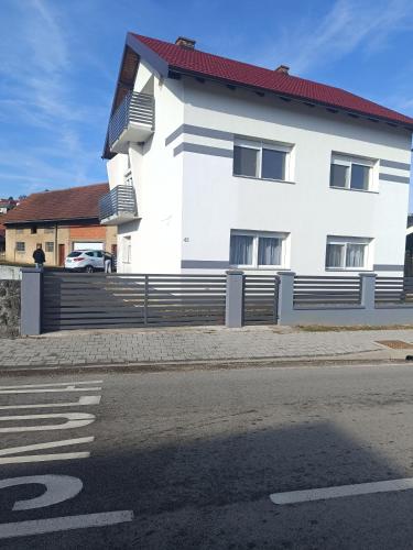 a white house with a fence next to a street at Apartman Katić in Varaždinske Toplice