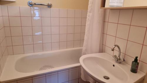 een badkamer met een wit bad en een wastafel bij Chez Mady - Terrasse, Vue Montagne & Proche Ski in Bussang