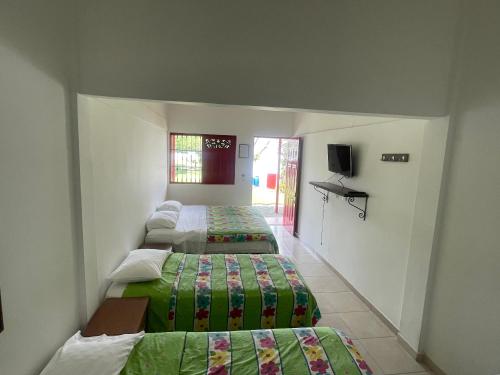 a bedroom with two beds and a tv in it at Finca Hotel Santana Campestre Quindio in Quimbaya