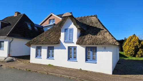 a white house with a thatched roof at Holiday Homes Buchholz in Büsum
