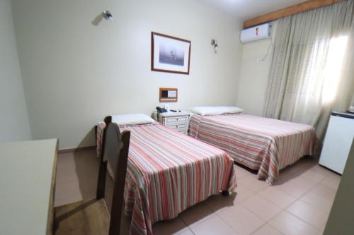 a hotel room with two beds and a window at Mariano Palace Hotel in Campinas