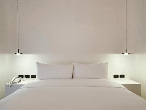 a bedroom with a white bed with two lights at Hope Hotel Tainan - Kangle Branch in Tainan