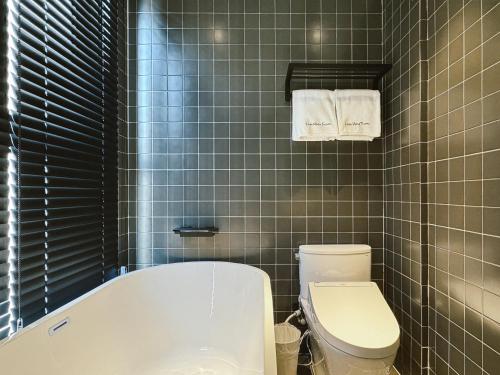 a bathroom with a bath tub and a toilet at Hope Hotel Tainan - Kangle Branch in Tainan