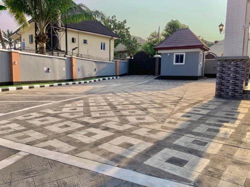 an empty parking lot with a building and palm trees at Oxford Villa Apartment in Nnewi