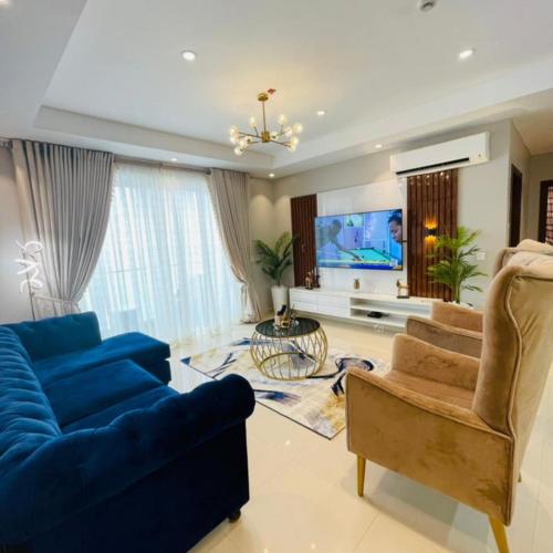 a living room with a blue couch and a tv at Oxford Villa Apartment in Nnewi