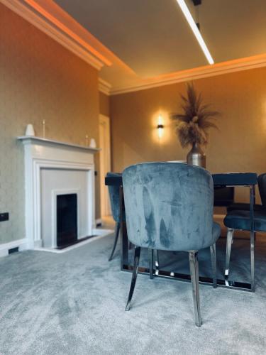 a living room with a blue chair and a fireplace at Red Roofs - 5BR Luxury - Large Gardens - EV Point - Near Edinburgh in Newtongrange