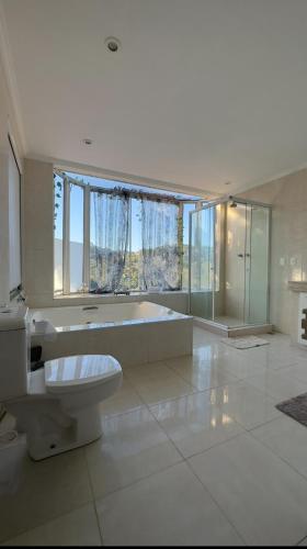 a large bathroom with a tub and a toilet and a bath tub at Casa Girassol in Teresópolis