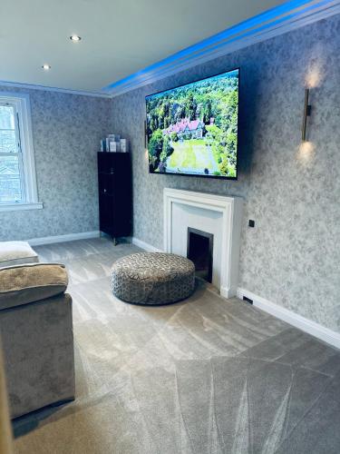 a living room with a tv hanging above a fireplace at Red Roofs - 5BR Luxury - Large Gardens - EV Point - Near Edinburgh in Newtongrange