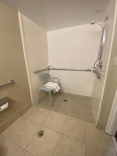 a small bathroom with a shower and a chair at Concord Suites by IHG in Concord