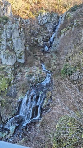 a waterfall on the side of a rocky hill at Maison La vie de l'Aubrac - Gîte Lo Bel Peis in Saint-Symphorien-de-Thénières