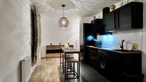 une cuisine avec des placards noirs, une table et un tabouret dans l'établissement Bel appartement chic et cosy Rungis, à Rungis