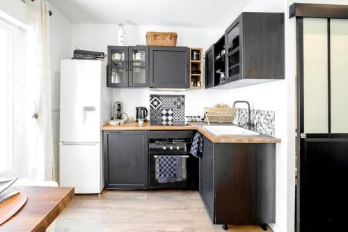 - une cuisine avec des armoires noires et un réfrigérateur blanc dans l'établissement Cosy aparthotel Downtown, à Sète