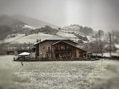 a house in a field with a hill in the background at Posada El Corcal de Liébana in Tama
