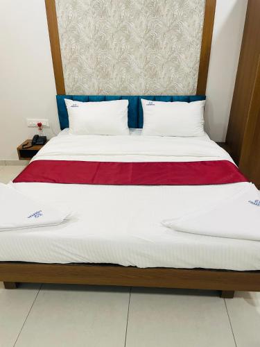 a bed with two white pillows and a red blanket at Hotel Coastal Empire in Belgaum