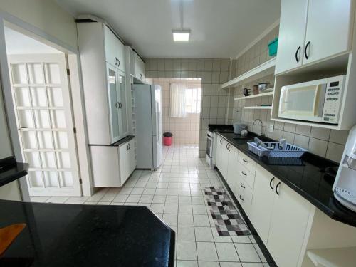 a kitchen with white cabinets and a black counter top at Amplo Apto Esquina Av Brasil in Balneário Camboriú
