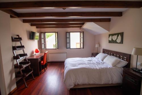 a bedroom with a bed and a desk and windows at Ático espectacular Comillas a 2 Km in Liandres