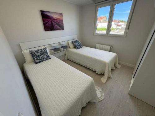 a small bedroom with two beds and a window at Apartamento Araceli in Suances