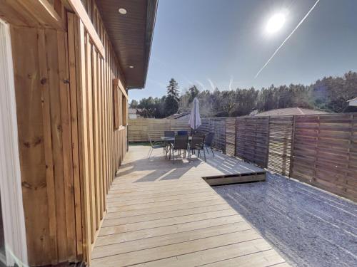 une terrasse en bois avec une table et des chaises dessus dans l'établissement Le Baleste - Duplex Cosy, à Mimizan