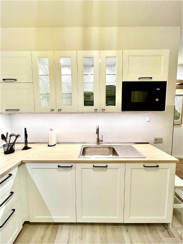 a white kitchen with a sink and a microwave at Chianti 67 Home Holiday in Castelnuovo Berardenga