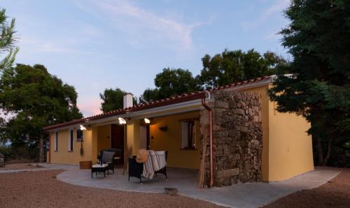 a small yellow house with a table and chairs at Lo Stazzo Multa Bianca Relax Assoluto nella Natura in Pedrumalu