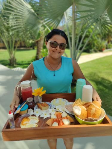 Una mujer sentada en una bandeja de comida para el desayuno. en BEACH VILLA Camurupim, en Guajirú