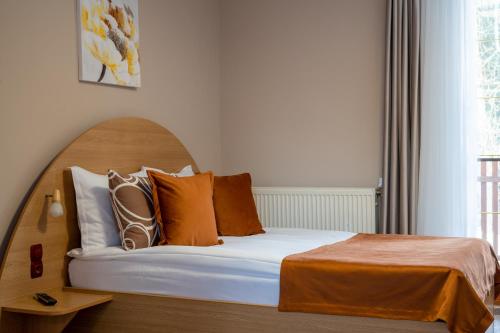 a bedroom with a bed with orange and white pillows at Vila Parc in Sovata