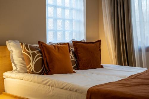 a bed with brown and white pillows and a window at Vila Parc in Sovata