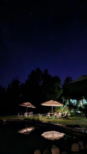 three tables and chairs with umbrellas at night at Hostal Macal in Talca