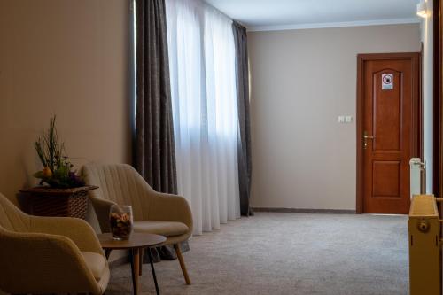a living room with chairs and a table and a door at Vila Parc in Sovata