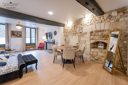 - un salon avec un mur en pierre, une table et des chaises dans l'établissement Le Palais de Velours (Centre-Ville Historique), à Auxerre