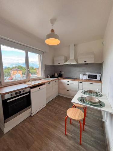 une cuisine avec des armoires blanches et une table et des chaises dans l'établissement LE POP appartement contemporain avec terrasse et parking, à Bonneville