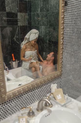 a man and a woman in a bathroom mirror at Casa Lucia Hotel Boutique in Mérida