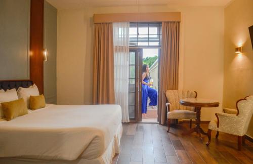 a hotel room with a bed and a woman looking out the door at Casa Lucia Hotel Boutique in Mérida