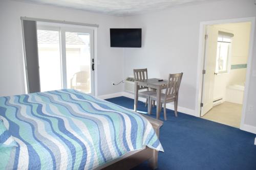 a bedroom with a bed and a table and a chair at Rhea's Inn by the Sea in Middletown